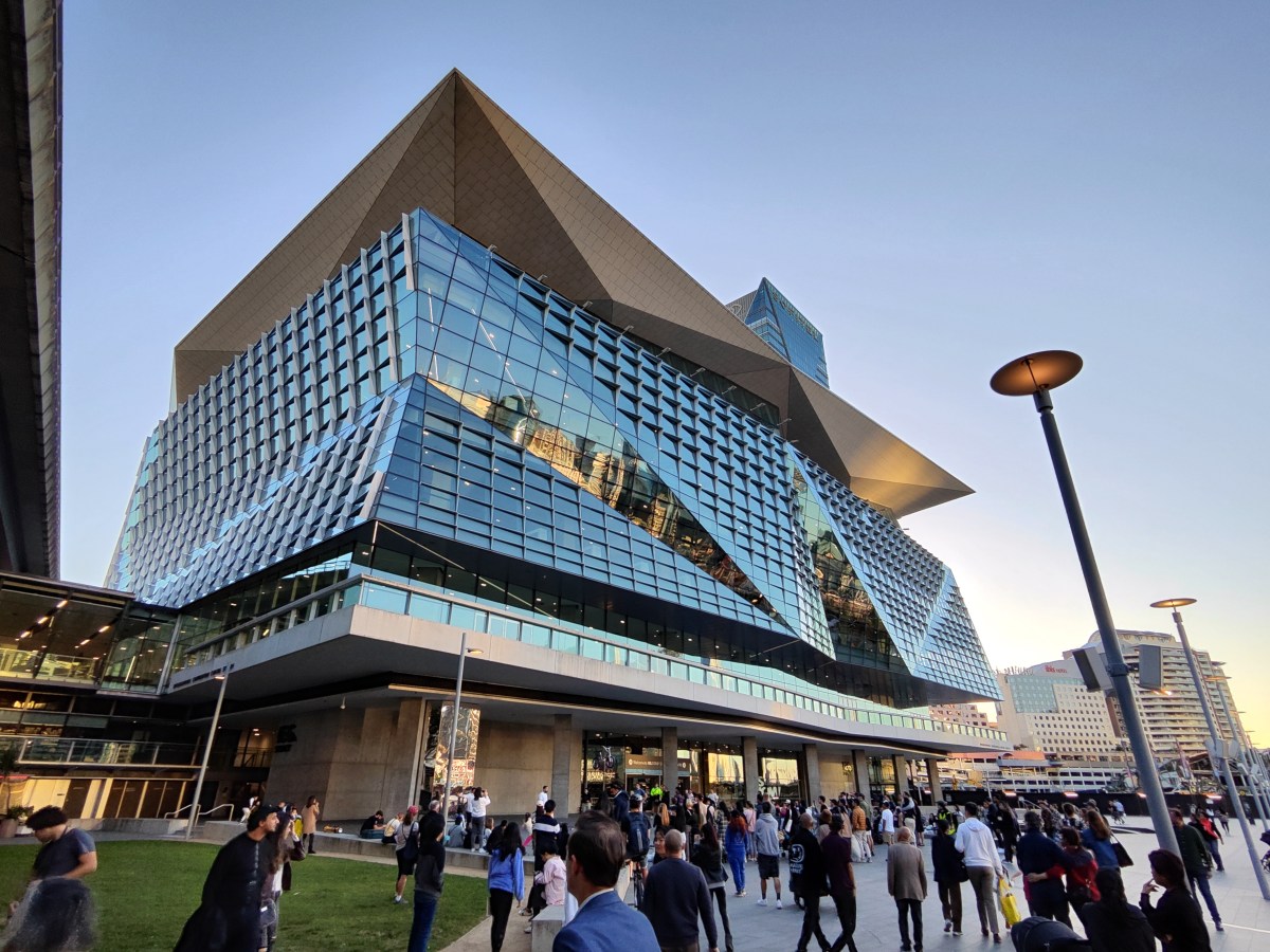 Sydney modern skyline viewed at Darling Harbor. People walking on the pedestrian zone in central Sydney.