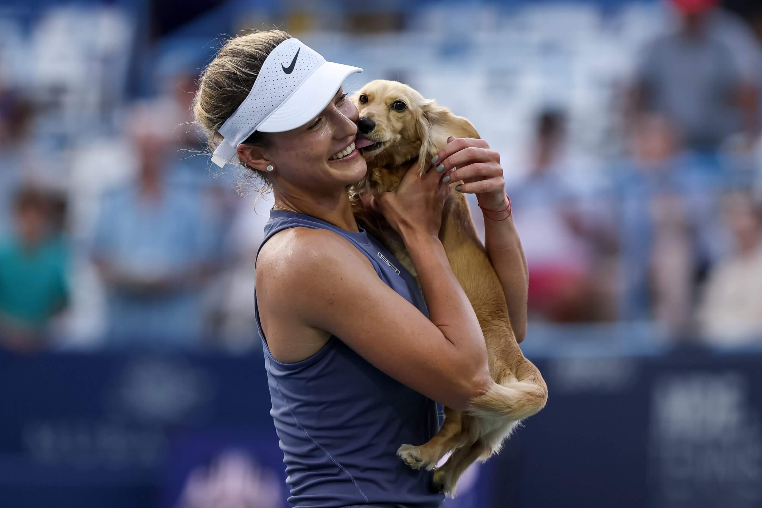 Anna Kalinskaya holds her small light brown dachsund as she kisses her owner's face.