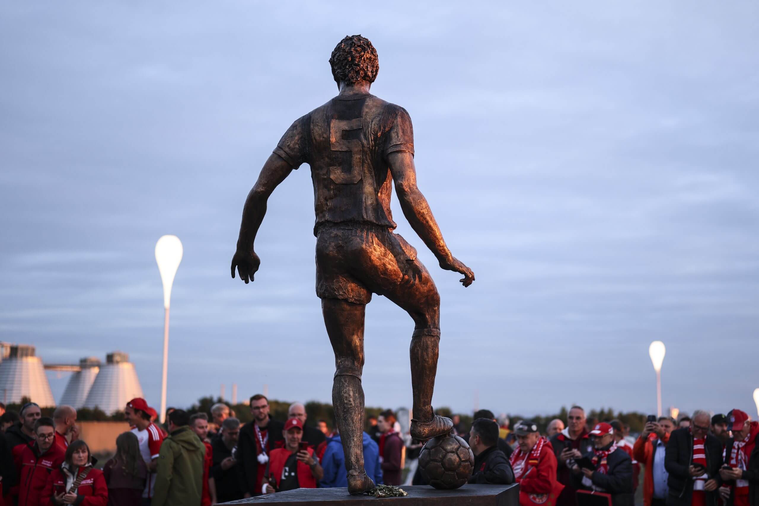 Fans take photographs of a bronze statue of Der Kaiser outside the Allianz Arena
