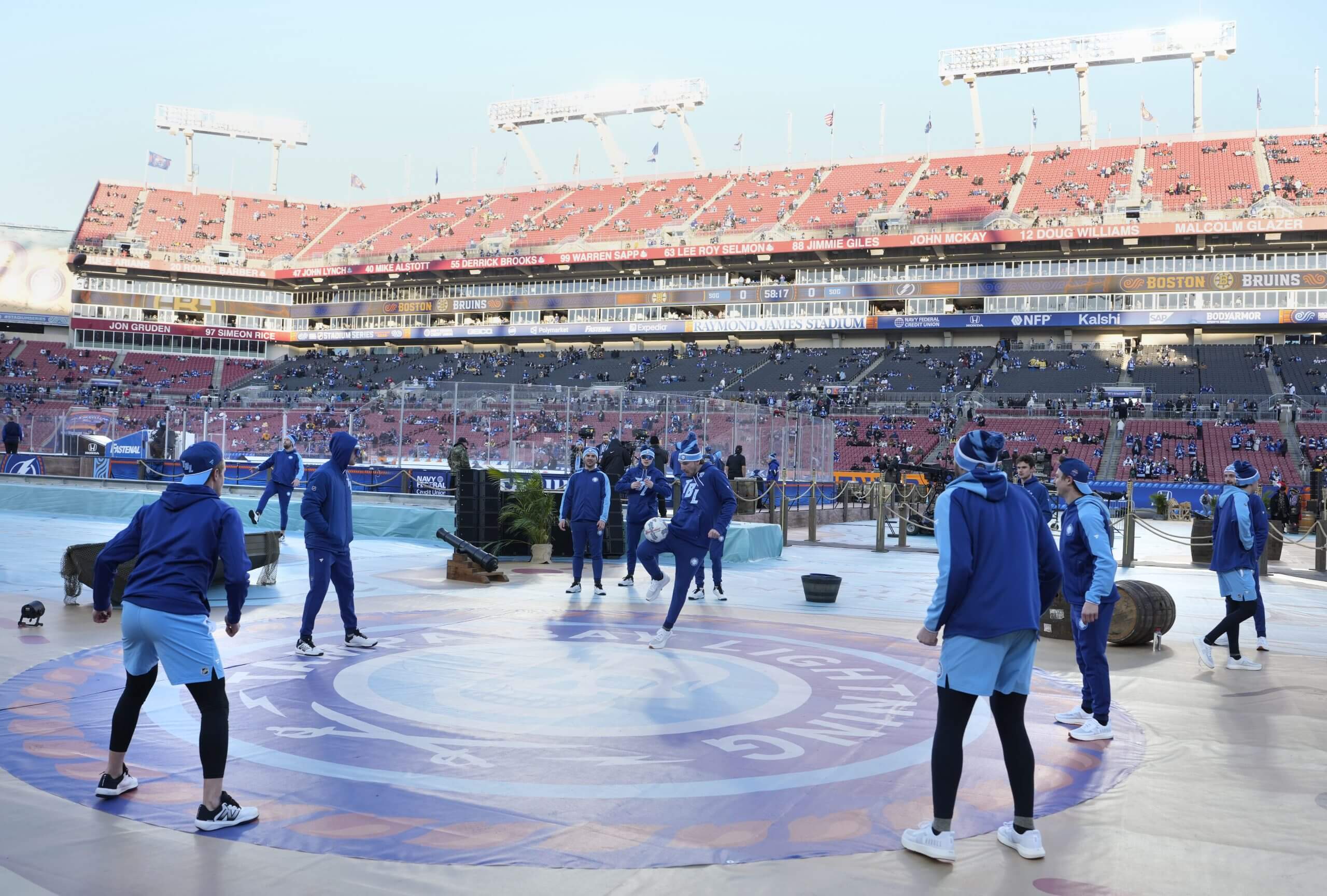 Members of the Tampa Bay Lightning kick around a soccer ball at an outdoor game.