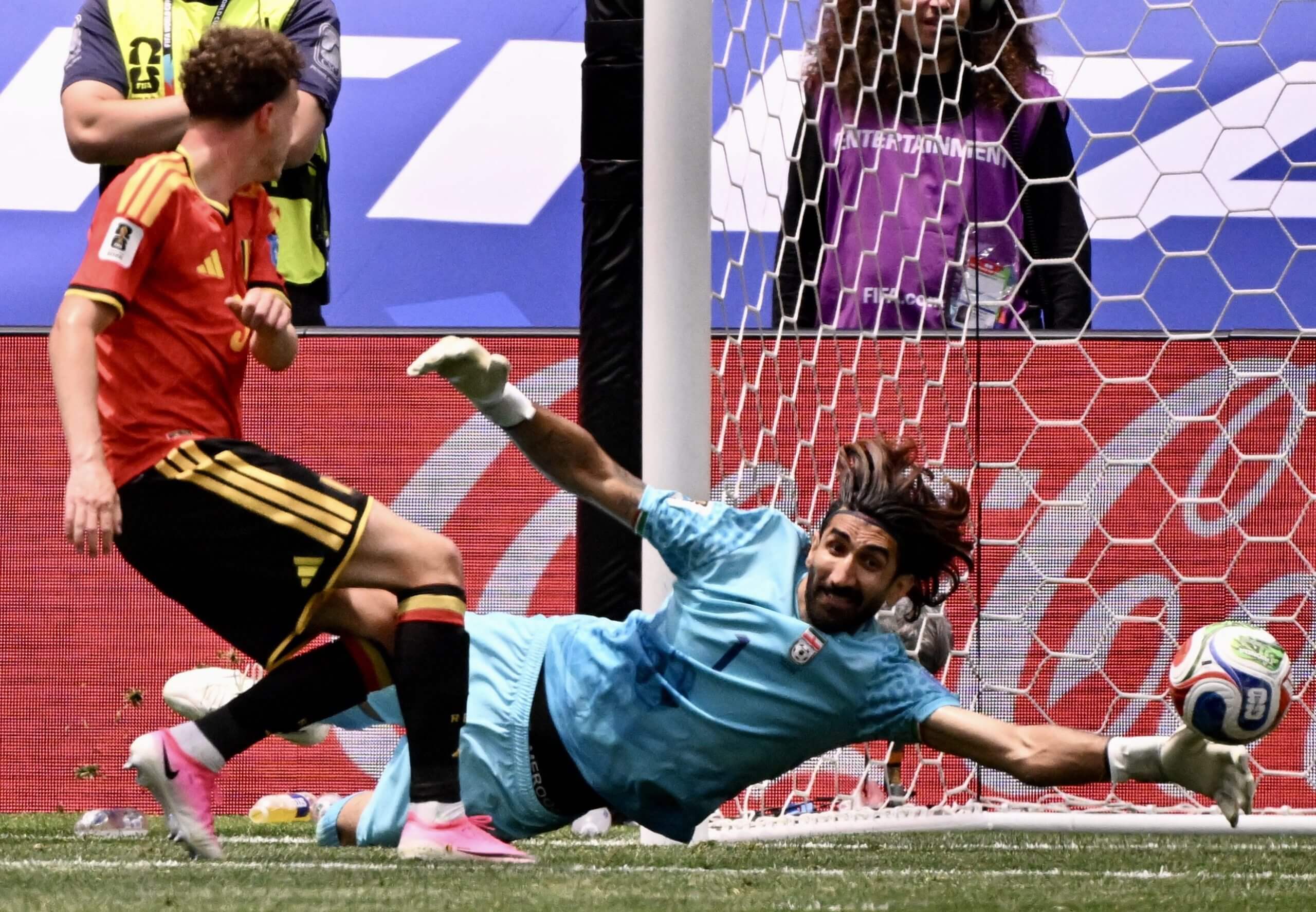 A goalkeeper dives to his left to palm a football away