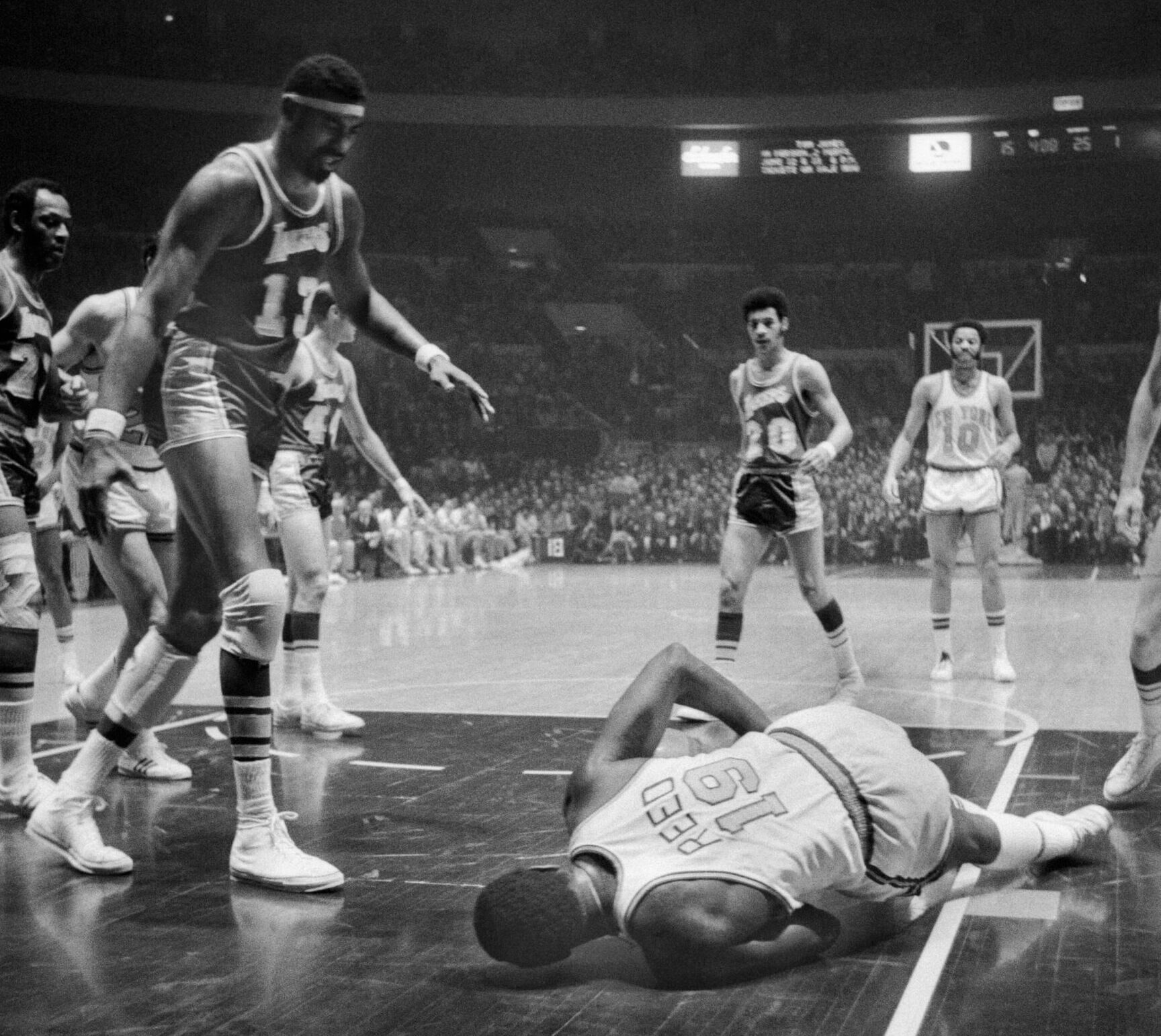 Willis Reed goes down with a leg injury in Game 5 during the 1970 NBA championship as Lakers big man Wilt Chamberlain stands and watches.
