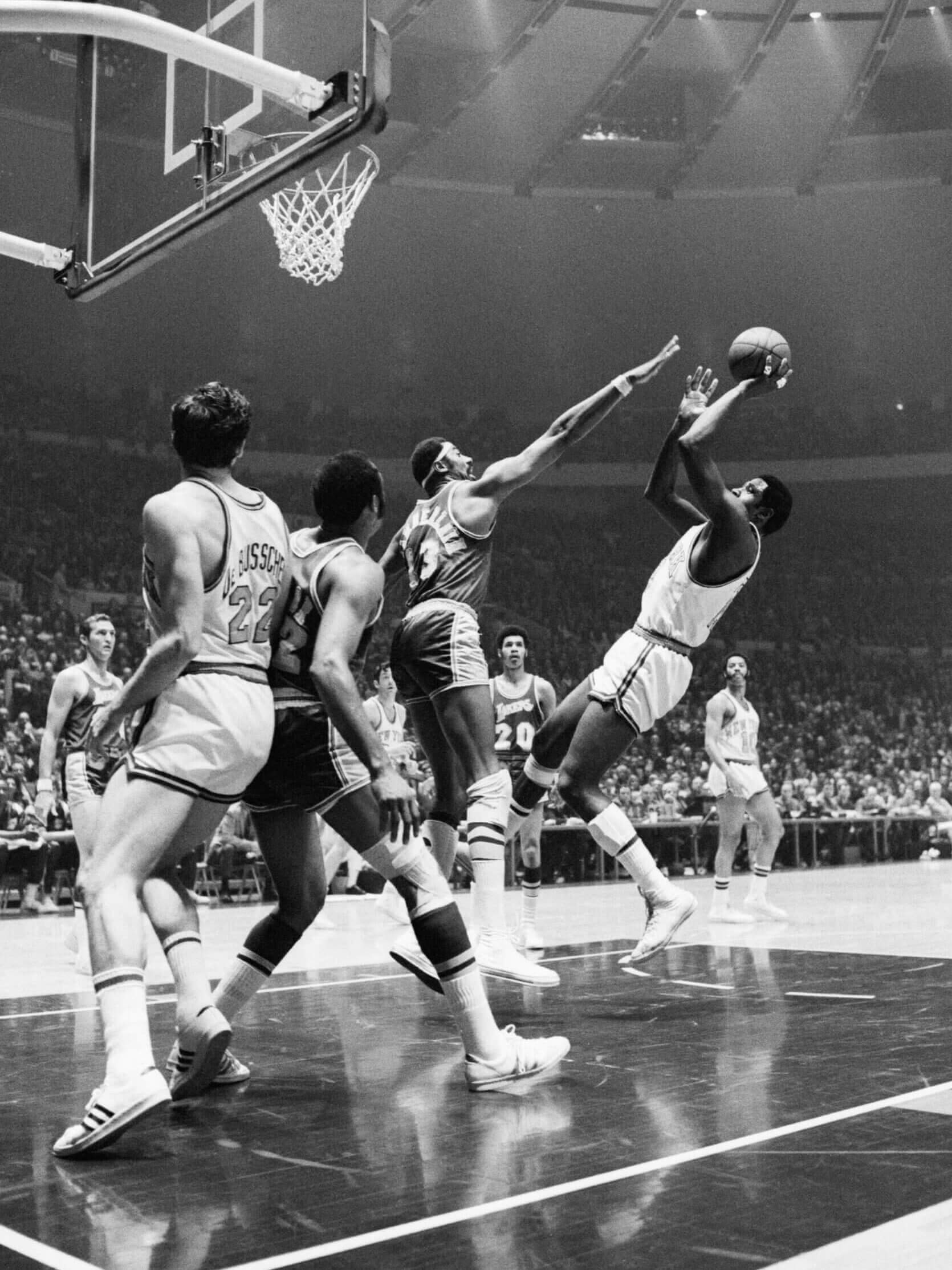 Willis Reed attempts shoots over the outstretched arm of Wilt Chamberlain as Dave DeBusschere (22) and Elgin Baylor jockey for position. Willis' 37 points and Cazzie Russell's fourth-quarter spark led the Knicks to a 124-112 victory in the series opener in Madison Square Garden.