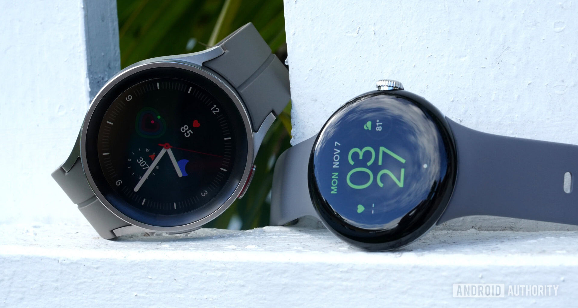 A Google Pixel Watch rests alongside a Galaxy Watch 5 pro.