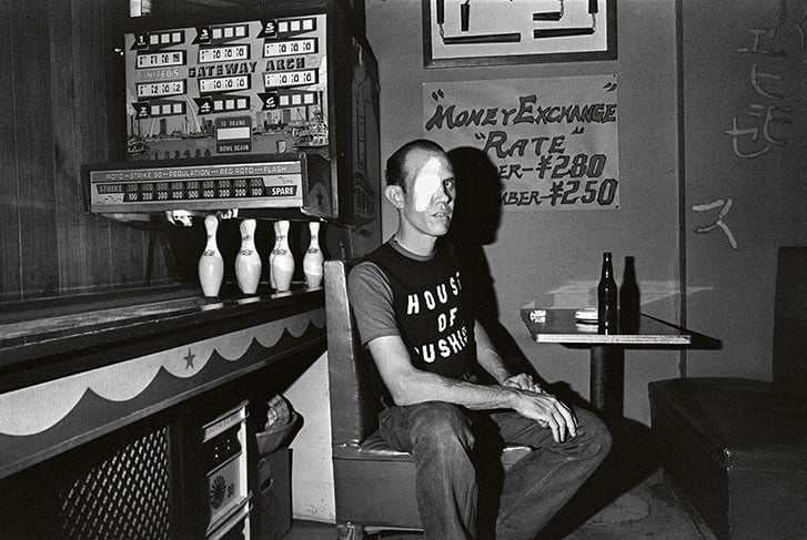 A man with a bandaged eye sits in a restaurant booth.