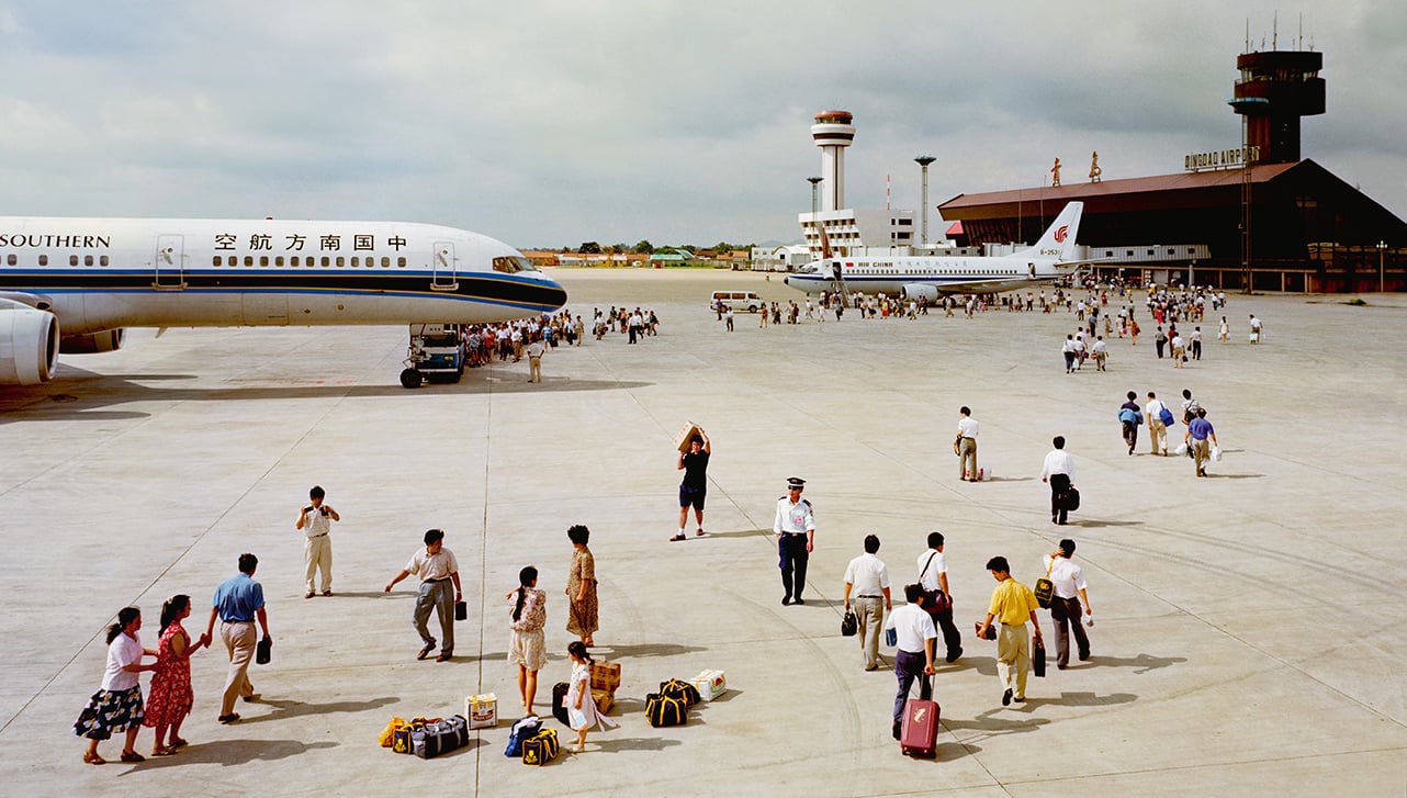 People walking to and from passenger planes on an airport tarmac.