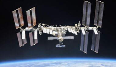ISS leak: Space station made of linked cylinders with 4 huge solar panels at each end floating above Earth.