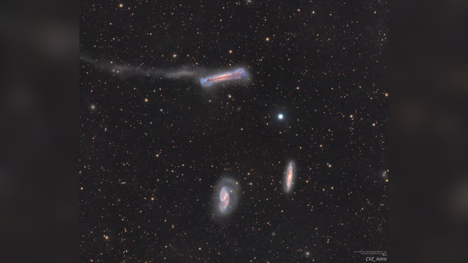 A trio of galaxies are pictured shining in deep space against a starfield dotted with more distant galaxies.