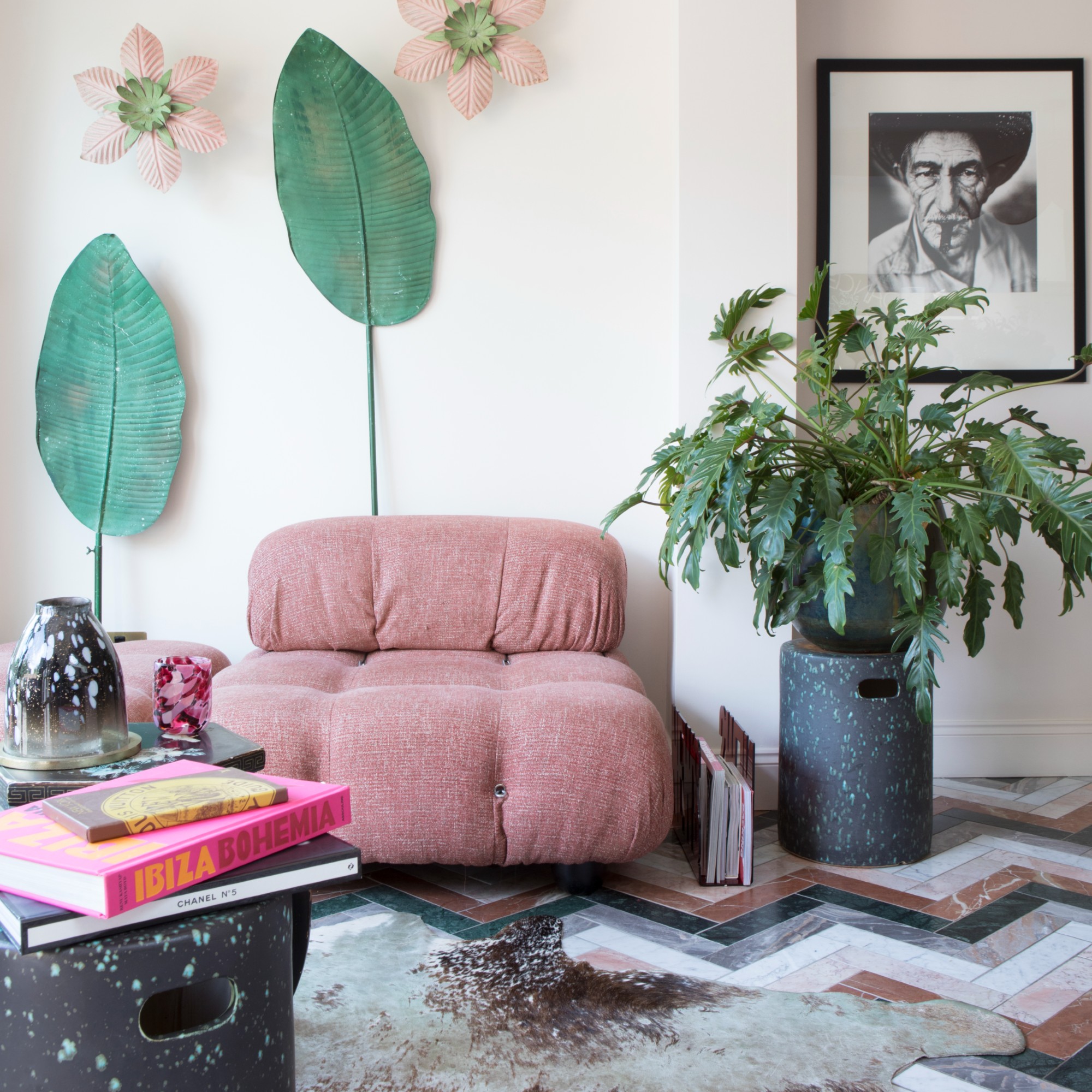 A snug with a patterned marble floor and a modular pink modern sofa with side tables used for displaying coffee table books and candles