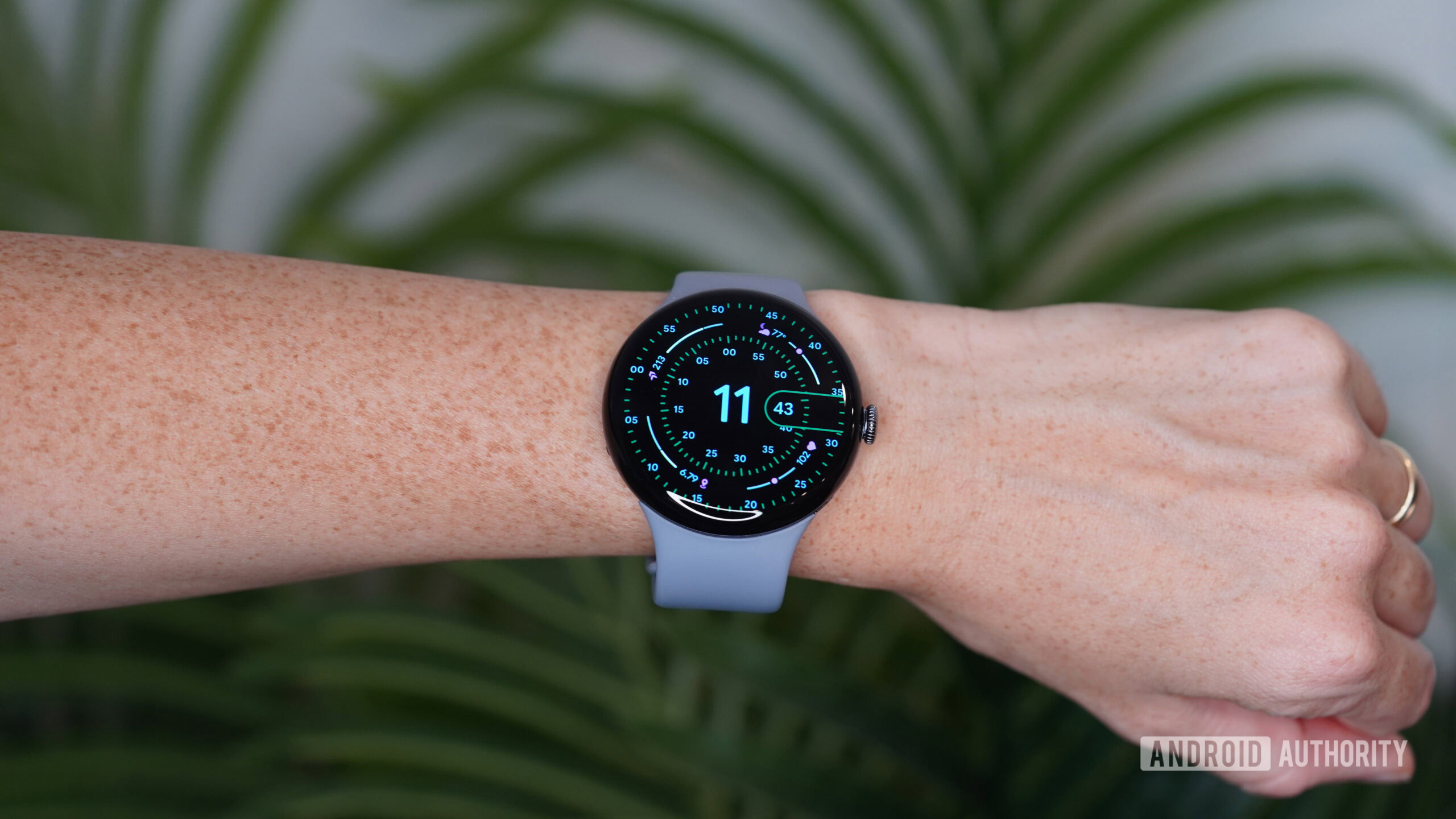 A Pixel Watch 4 on a user's wrist displays a watch face.