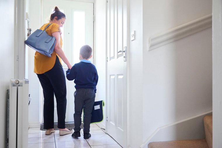 A mother and son on their way out of the front door for his first day at school