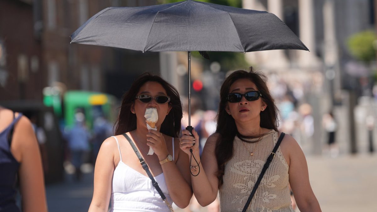People shield from the sun under an umbrella, on the Millennium Bridge in London. Temperatures could reach 32C in parts of central and southern England on Friday and are expected to remain high into the weekend, with a yellow heat health alert in place for all regions in England until July 15. Picture date: Friday July 11, 2025. PA Photo. Photo credit should read: Yui Mok/PA Wire