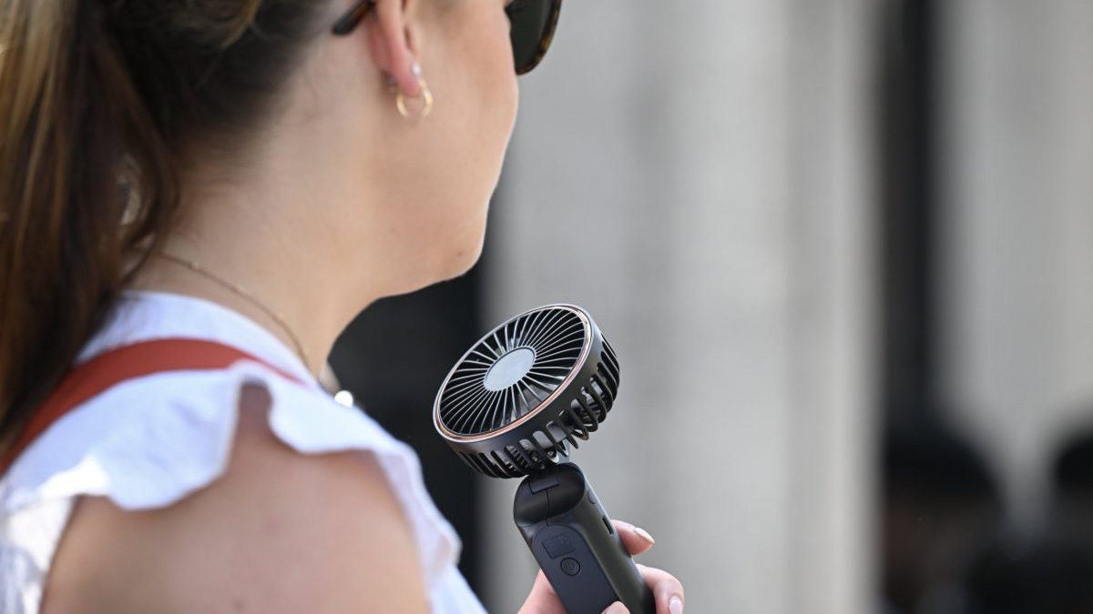 LONDON, UNITED KINGDOM AUGUST 12: A woman uses a portable fan to cool down in London as the UK Health Security Agency (UKHSA) issues an amber extreme heat health alert for East Midlands, West Midlands, East of England, London and South East on August 12, 2025. The rest of the country remains under a yellow heat warning, with temperatures expected to exceed 35??C in some areas. (Photo by Rasid Necati Aslim/Anadolu via Getty Images)