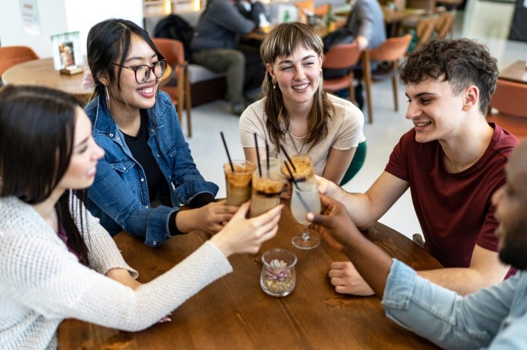 Cheerful diversity friends toasting with coffees in a coffee shop
