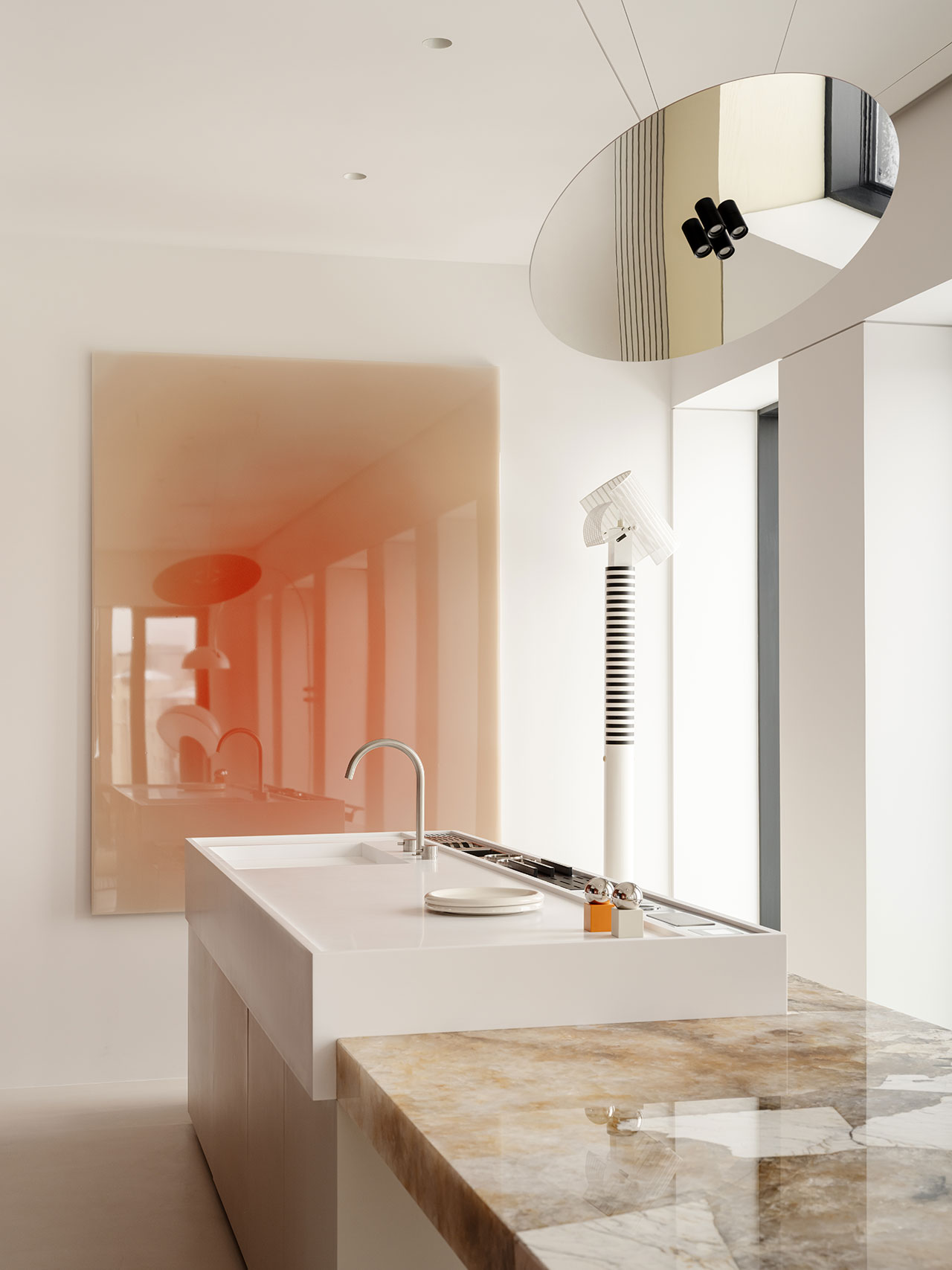 Minimalist Antwe kitchen with a marble countertop, white island sink, modern faucet, wall art featuring a gradient effect, and a circular mirror reflecting ceiling lights.