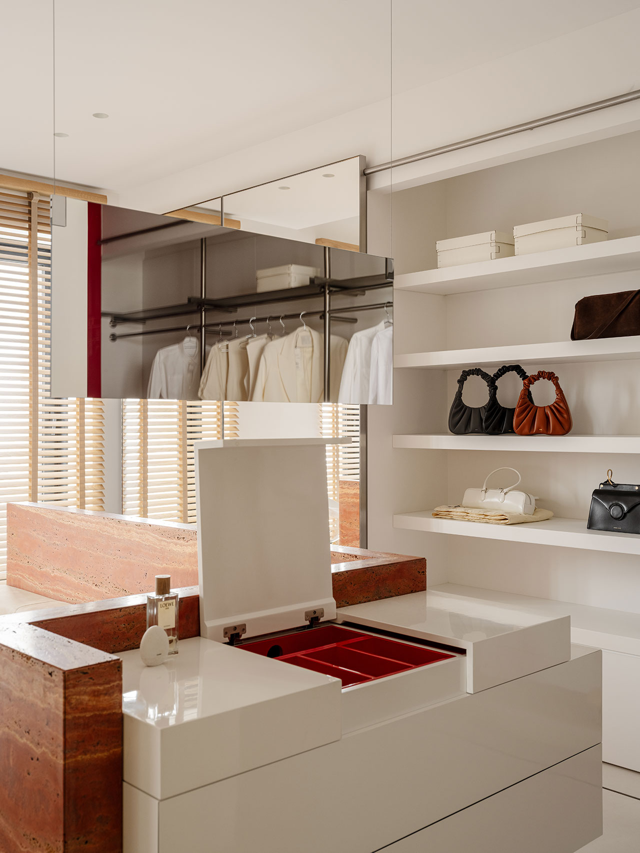 Modern Antwe walk-in closet with white shelves displaying handbags, a mirrored wall, hanging clothes, and a white jewelry box with an open lid on a glossy dresser.