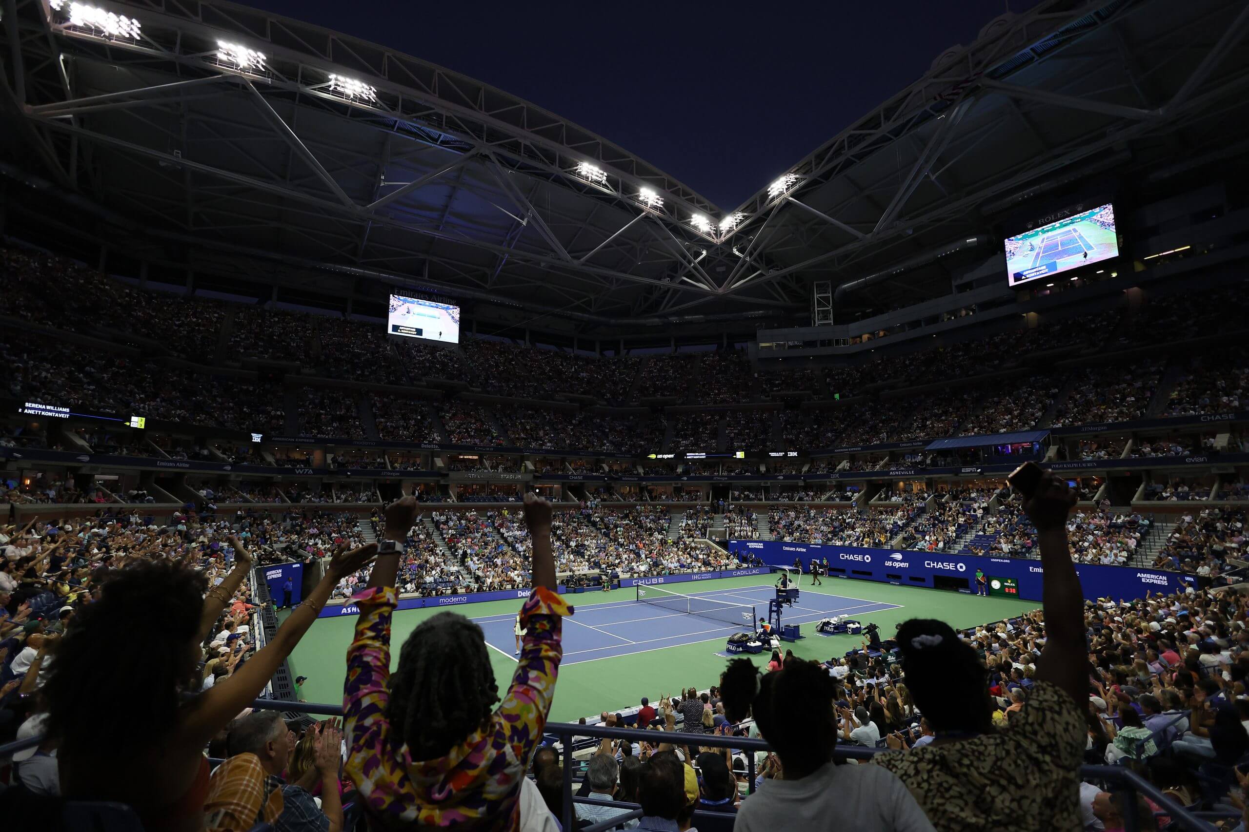 U.S. Open fans rise to celebrate Serena Williams on Arthur Ashe stadium at night.