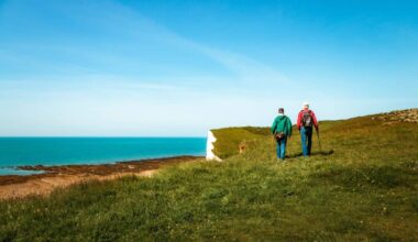 Rear view image depicting two men hiking together with the stunning backdrop of Seven Sisters cliffs in the south of England.