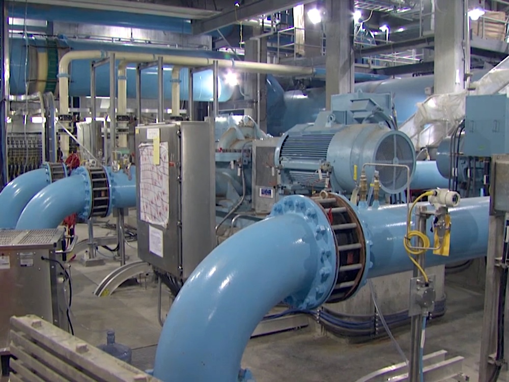 Large blue pipes in a large concrete room.