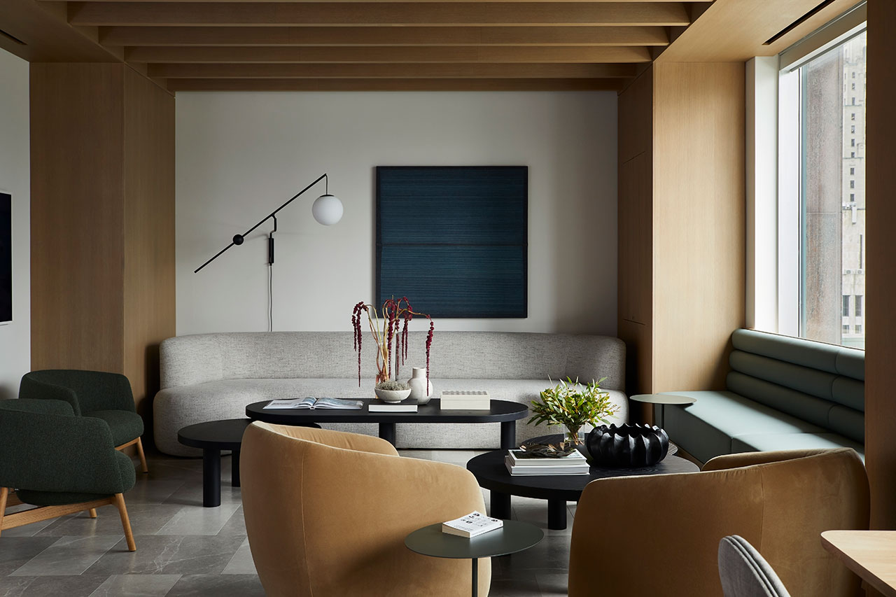Modern living room with neutral tones, featuring a light gray sofa, beige chairs, black tables, wall art, and large window with city view. Contemporary decor with minimalist design.