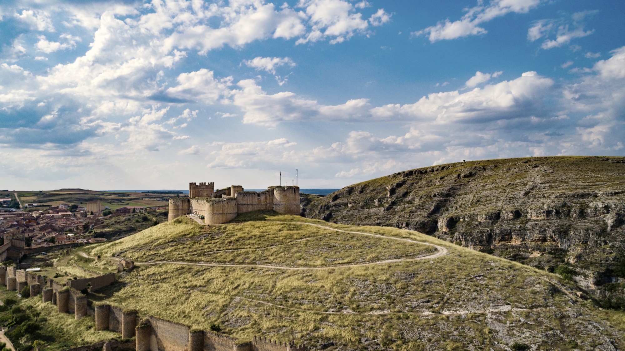 a castle sits on a small hill surrounded by a large wall.