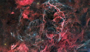 The starfield is filled with many red nebulas, areas
of dark dust, and light blue filaments. 
Please see the explanation for more detailed information.