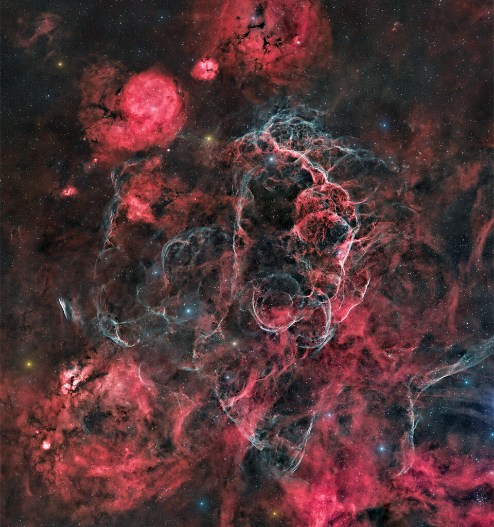 The starfield is filled with many red nebulas, areas
of dark dust, and light blue filaments. 
Please see the explanation for more detailed information.