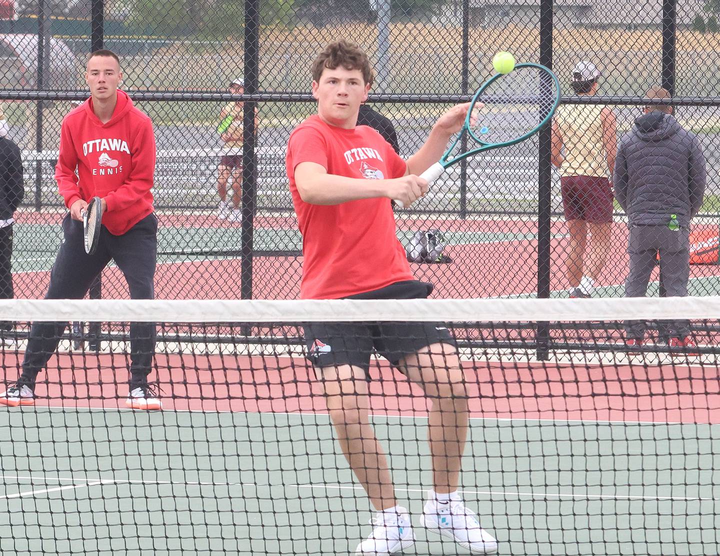 Ottawa's Ayden Sexton returns the ball as teammate Kaden Araujo watches during the Class 1A Sectional tennis meet this past season at the La Salle-Peru Township High School Athletic Complex in La Salle.