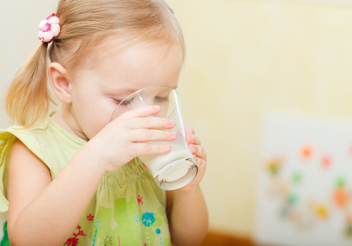 A toddler girl drinking milk.