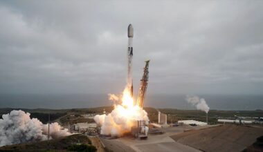 a white and black rocket lifts from a sea-front launch pad into an overcast sky
