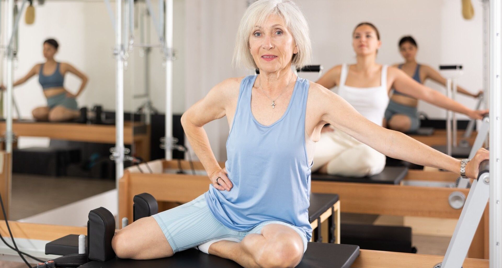 Mature woman in blue activewear in a reformer Pilates class