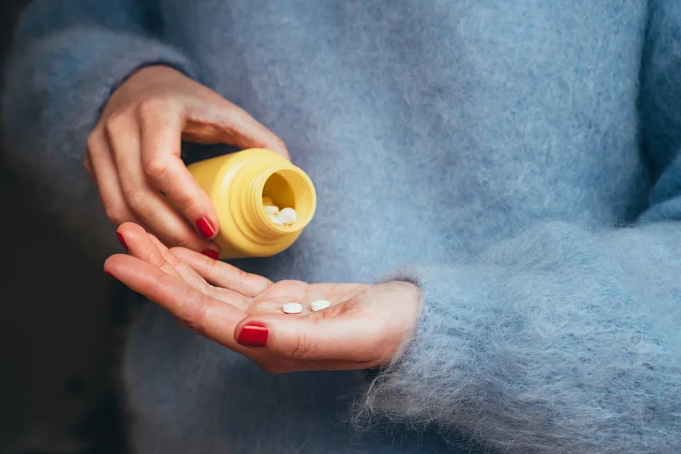 Anastasiia Voloshko/Getty Images - stock photo of a person holding tablets and a medicine bottle, representing personal healthcare, treatment, and responsible medication use at home