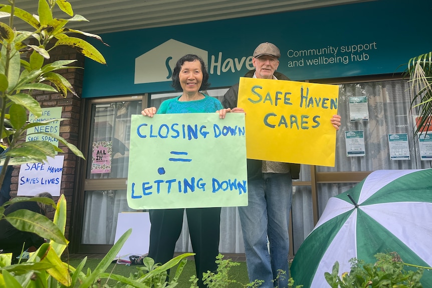 A man and a woman stand with sighs saying 'Safe Haven Cares' out side a pop up mental health centre in Murwillumbah NSW