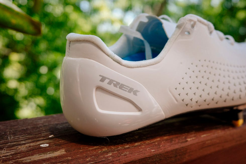 White Trek cycling shoe on wooden railing in sunlight. White Trek cycling shoe on wooden railing in sunlight.