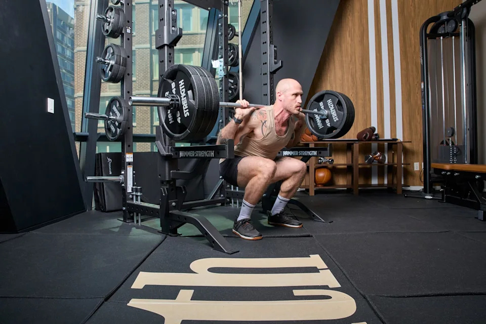 Man performing a squat with heavy weights in a gym.