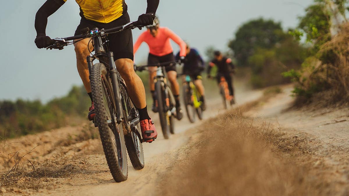 Mountain bikers ride on a dirt trail during a group ride.