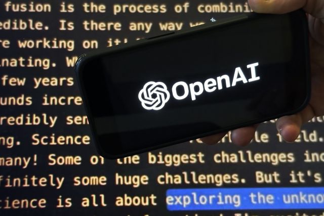 The OpenAI logo appears on a mobile phone in front of a screen showing part of the company website in this photo taken on Nov. 21, 2023 in New York. THE CANADIAN PRESS/AP-Peter Morgan