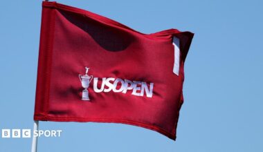 A red flag with an image of the US Open trophy, the words US Open and the number one on it, all in white.