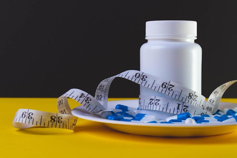 A pill bottle with a tape measure around it.