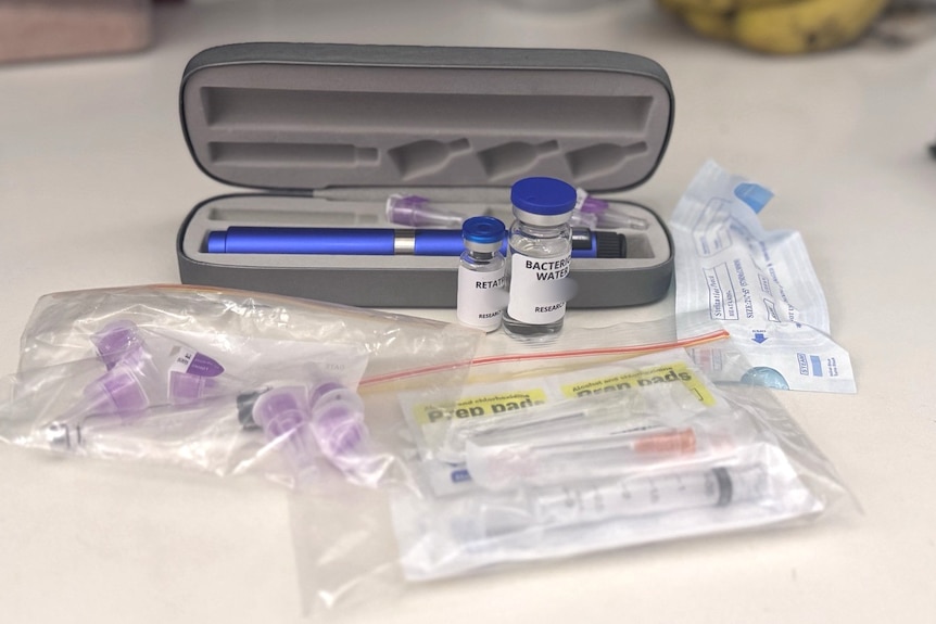 Vials and accompanying injectable accessories are layed out on a tbale