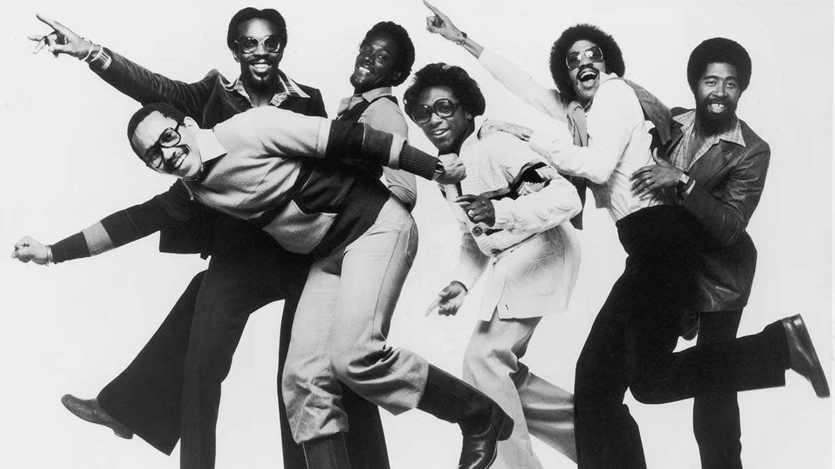 The Commodores band members posing in a studio portrait moving forward