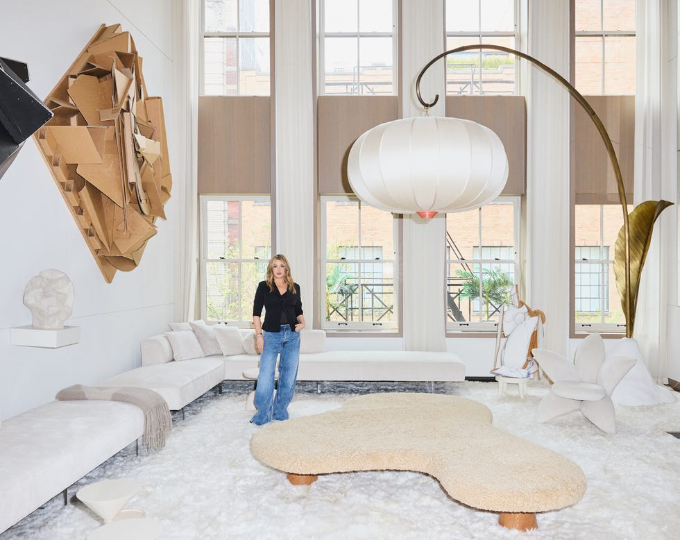 Woman standing in a modern, airy living room with abstract art and unique furniture.