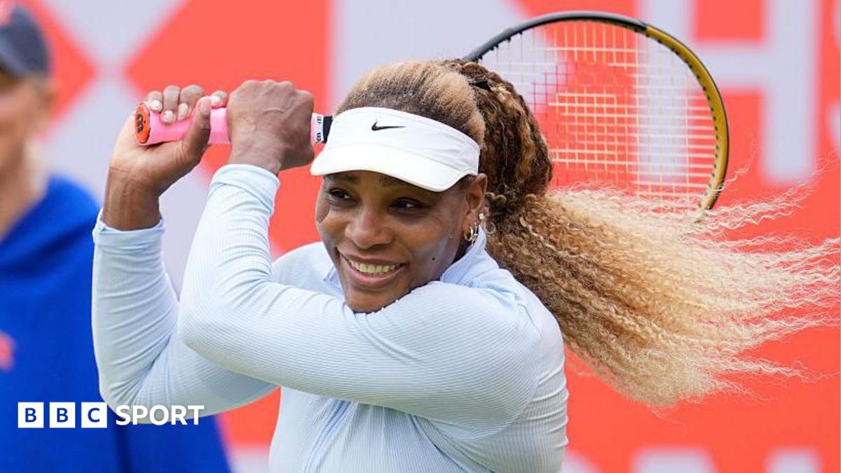 Serena Williams, wearing white and smiling, plays a backhand