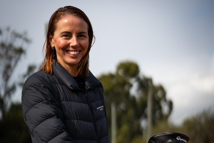 A photo of Ambre Perry with golf clubs.