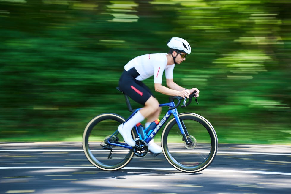 Cyclist in motion on a blue road bike in a forest setting. Cyclist in motion on a blue road bike in a forest setting.