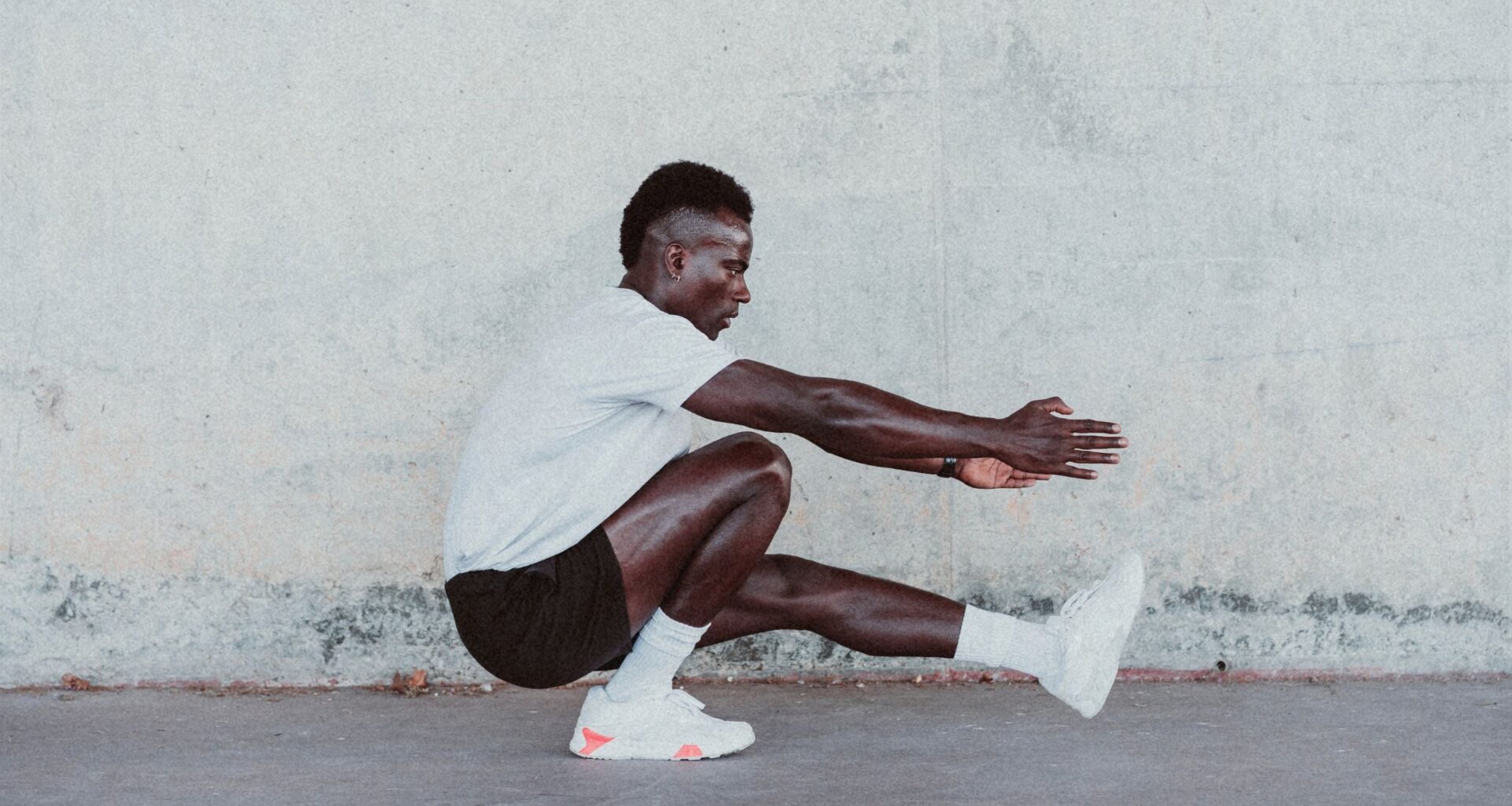 Male athlete doing exercise by white wall