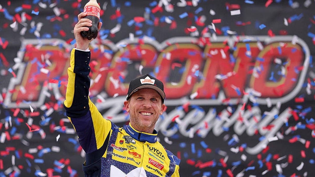 Denny Hamlin celebrating in victory lane at Pocono Raceway.
