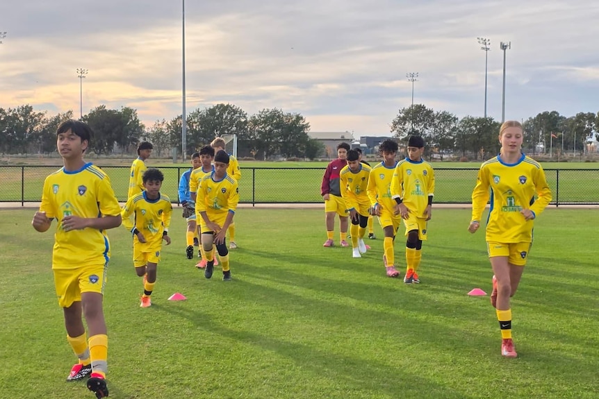 Twelve young soccer platers warming up on the grounds