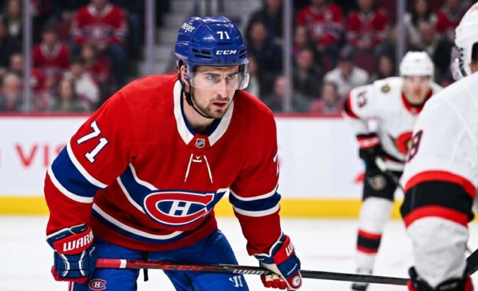 Montreal Canadiens forward Dylan Larkin (number 71) is captured in a red home jersey, skating with the puck in a high-quality NHL action photograph. The photo highlights his focus and skill, a key figure in recent trade speculation.