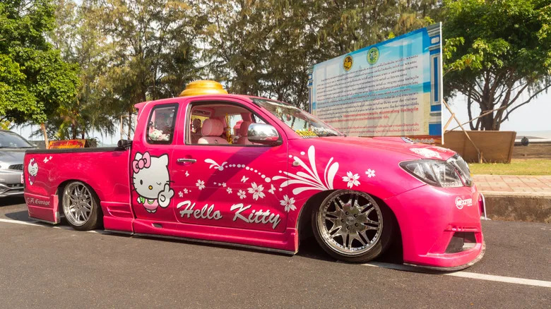 Car Tuning. Toyota Hilux Vigo Champ in pink color, Lexus logo, lowered suspension. Lowrider Toyota with 20 inch chrome wheels. Body kit, front and rear bumpers, side skirt
